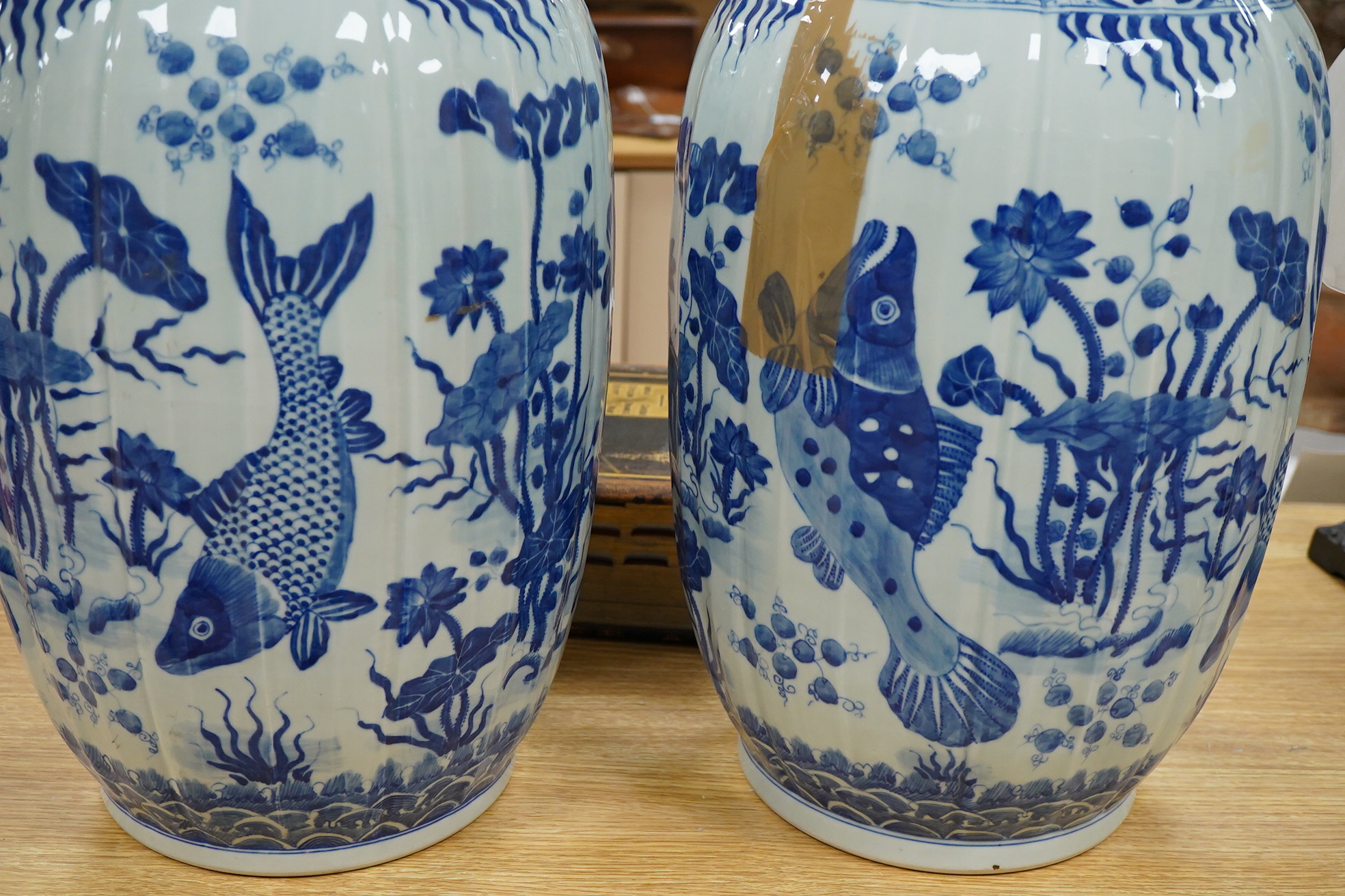 A large pair of Chinese blue and white ovoid jars and covers decorated with fish and lotus, 48cm high